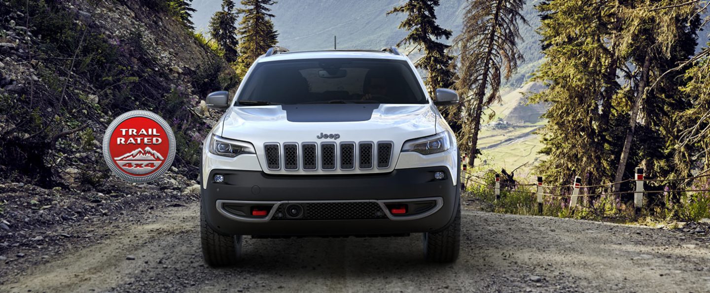 Trail Rated 4x4 logo. The front view of a 2021 Jeep Cherokee Trail Rated parked on a trail.