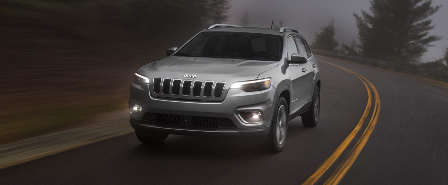 The 2021 Jeep Cherokee being driven at night with its headlamps and fog lamps lit.